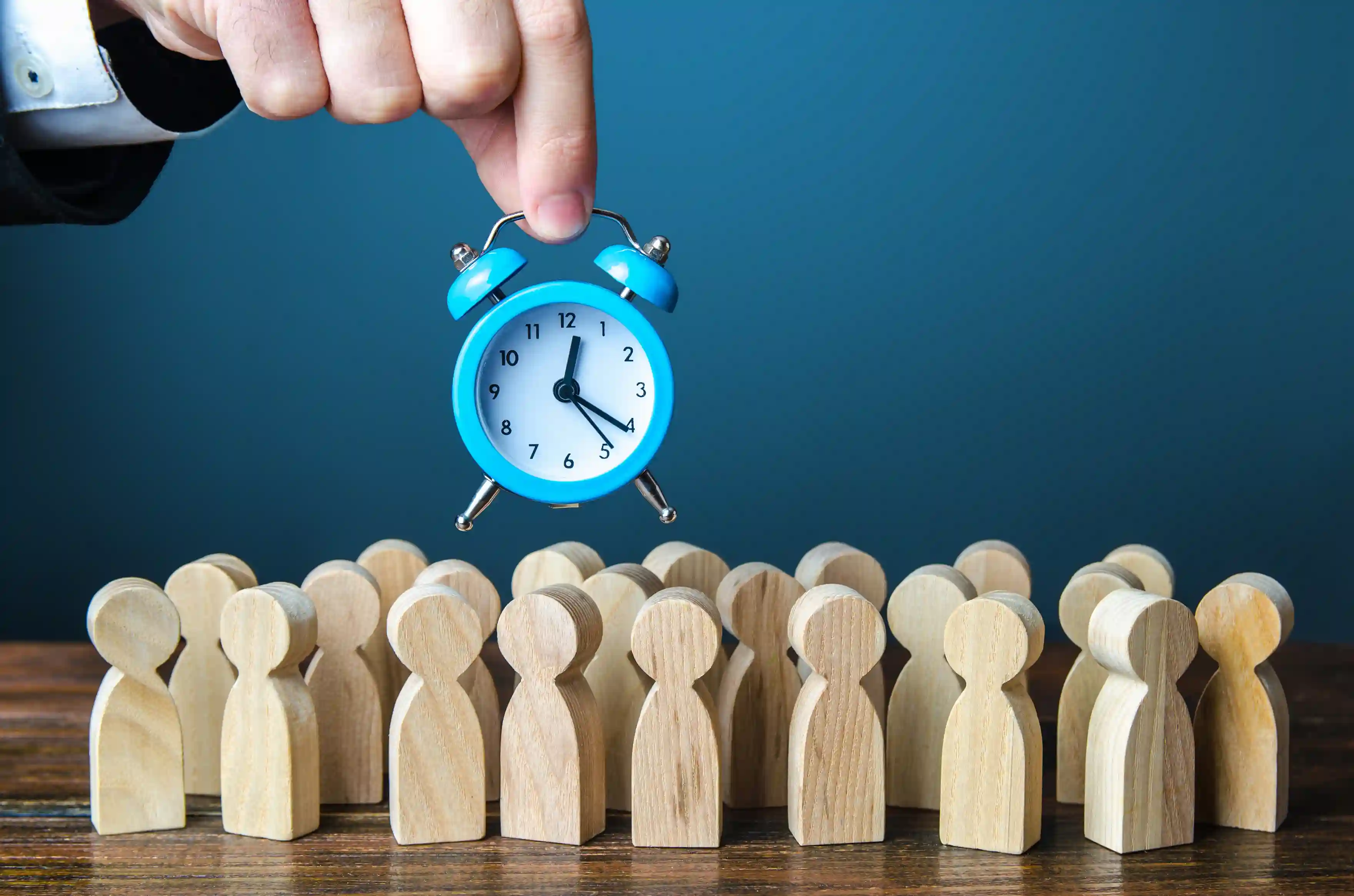 Alarm clock with wooden figures representing workforce time management
